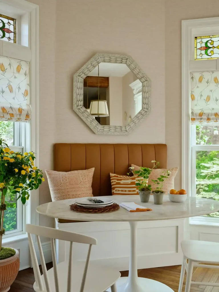 Small space with bench and oval table between windows to create a breakfast and dining area.

