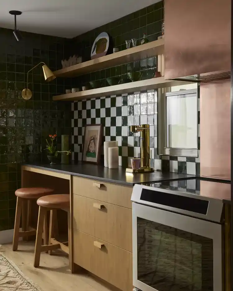 Black and white kitchen backsplash with checkerboard tiles, brass accents, cool-toned wood, and dark green tiles
