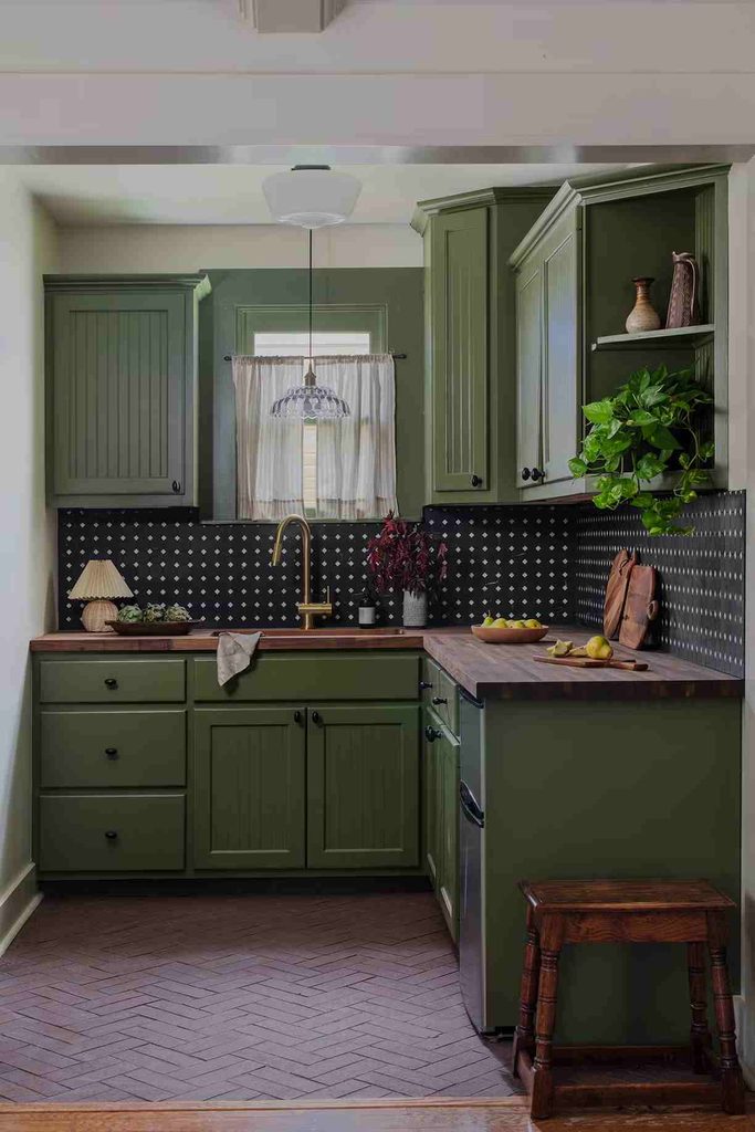 Black and white kitchen backsplash with a grid and diamond pattern, green cabinets, and a warm countertop