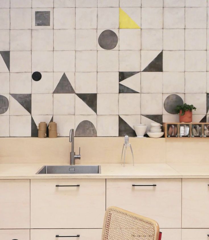 Black and white tiles arranged in a random geometric kitchen backsplash pattern with yellow accents