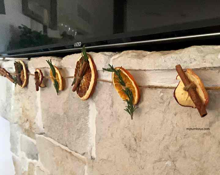 Cute Christmas craft with dried oranges, cinnamon and rosemary. A garland hanging from mantel.